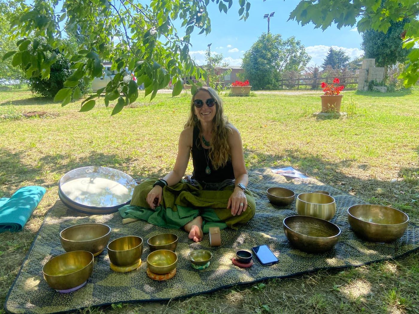 Barbara Visentin seduta sul prato in mezzo alle campane tibetane